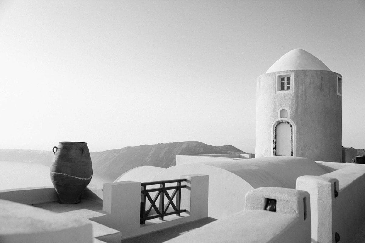 Whitewashed Mediterranean-style architecture with a domed roof, simple archways, and a single ceramic vase.