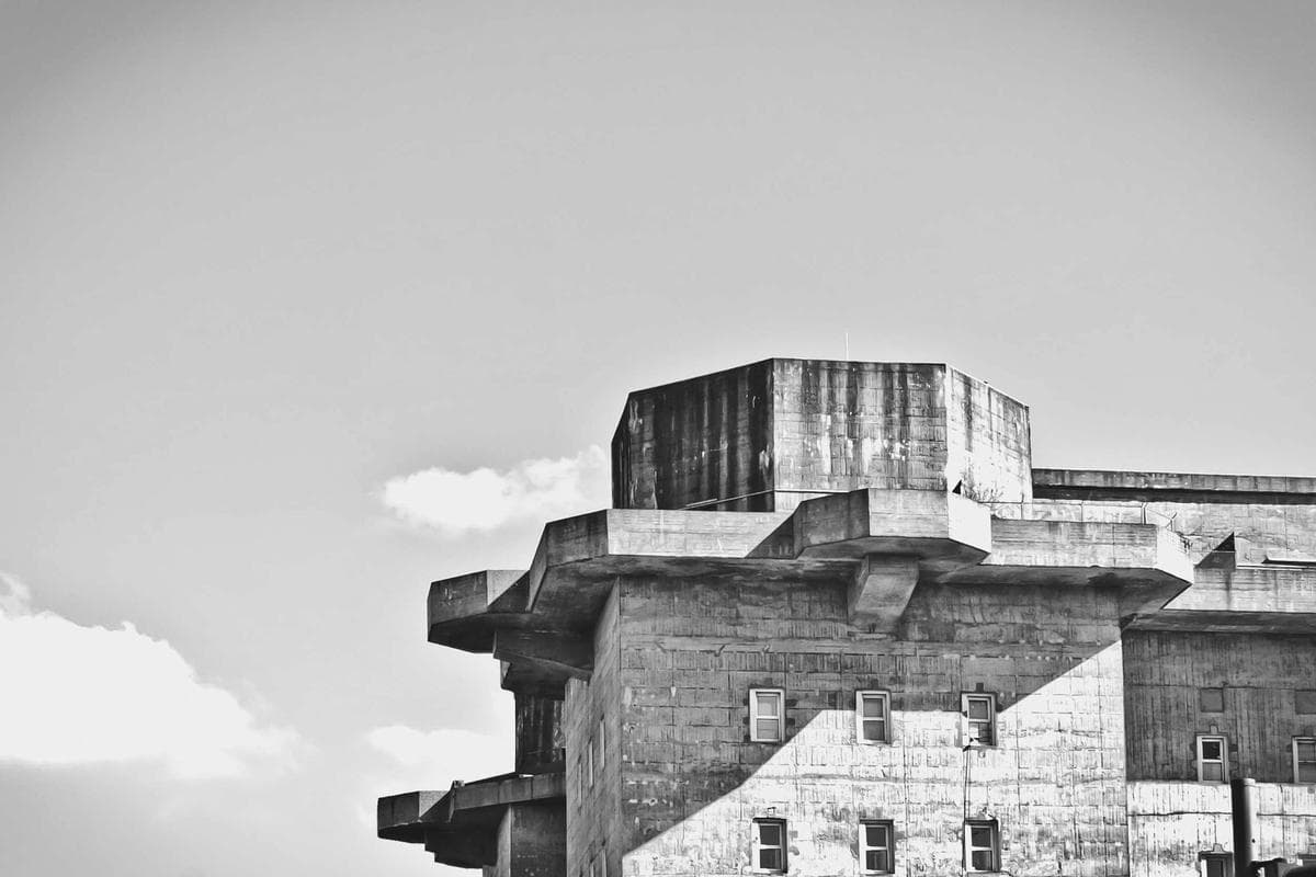 A brutalist concrete building set against a dramatic, cloud-filled sky.