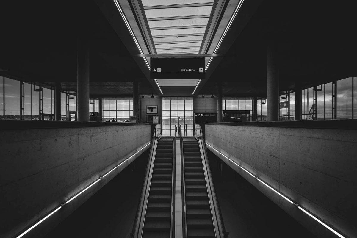 The interior of a modern building with sweeping escalators and geometric glass-and-steel architecture.